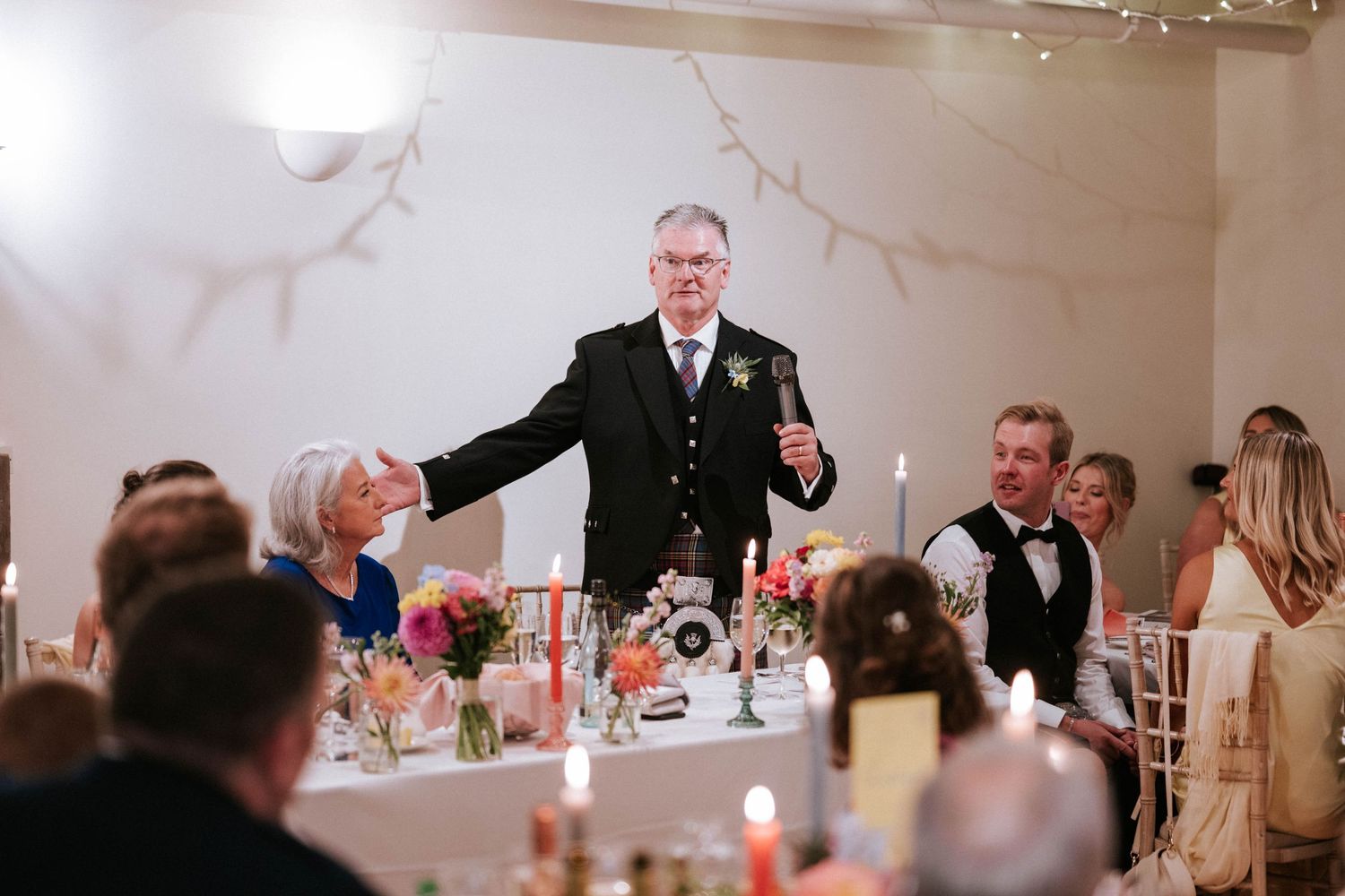 Wedding reception dinner setup with white linens and floral centerpieces in an elegant venue.