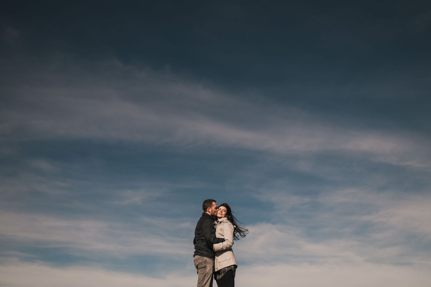 A dramatic wedding photo session against moody cloudy skies and mountain landscapes at sunset.