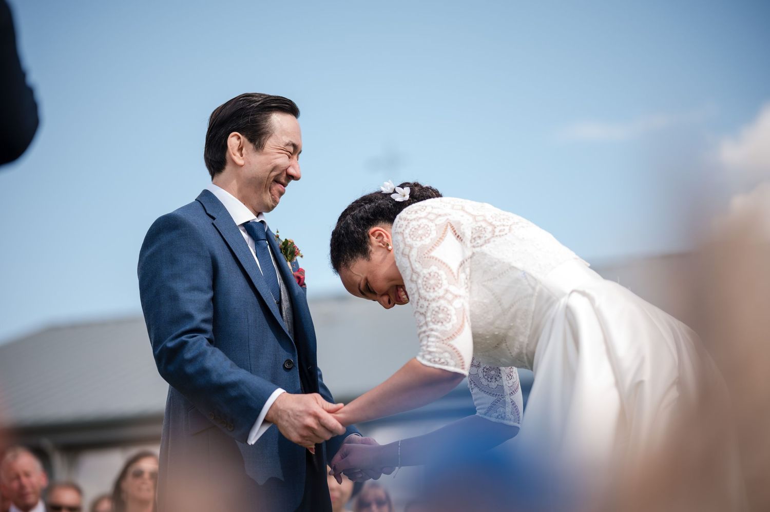 Wedding ceremony taking place outdoors under bright blue sky.