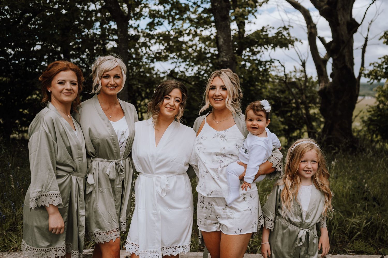 A group wearing coordinated robes pose together outdoors in a natural setting.
