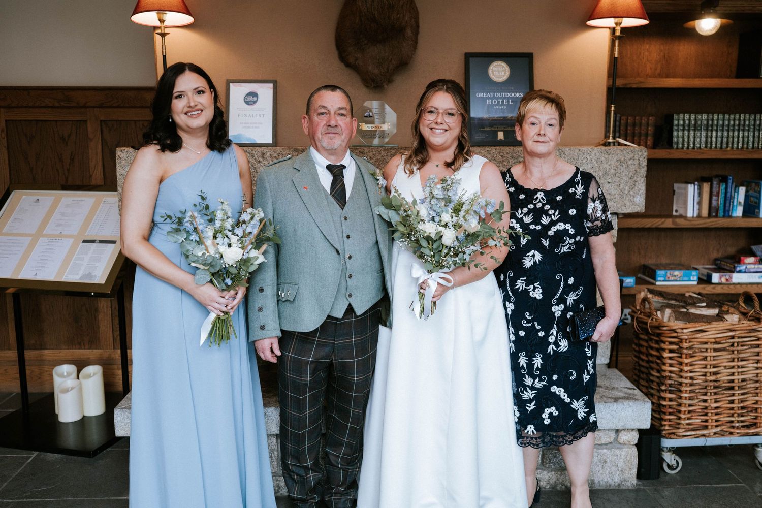 Wedding party poses with bouquets in elegant library setting with wood paneled walls.