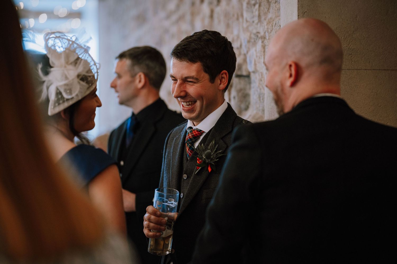 Guests chatting and holding drinks during an indoor wedding reception.