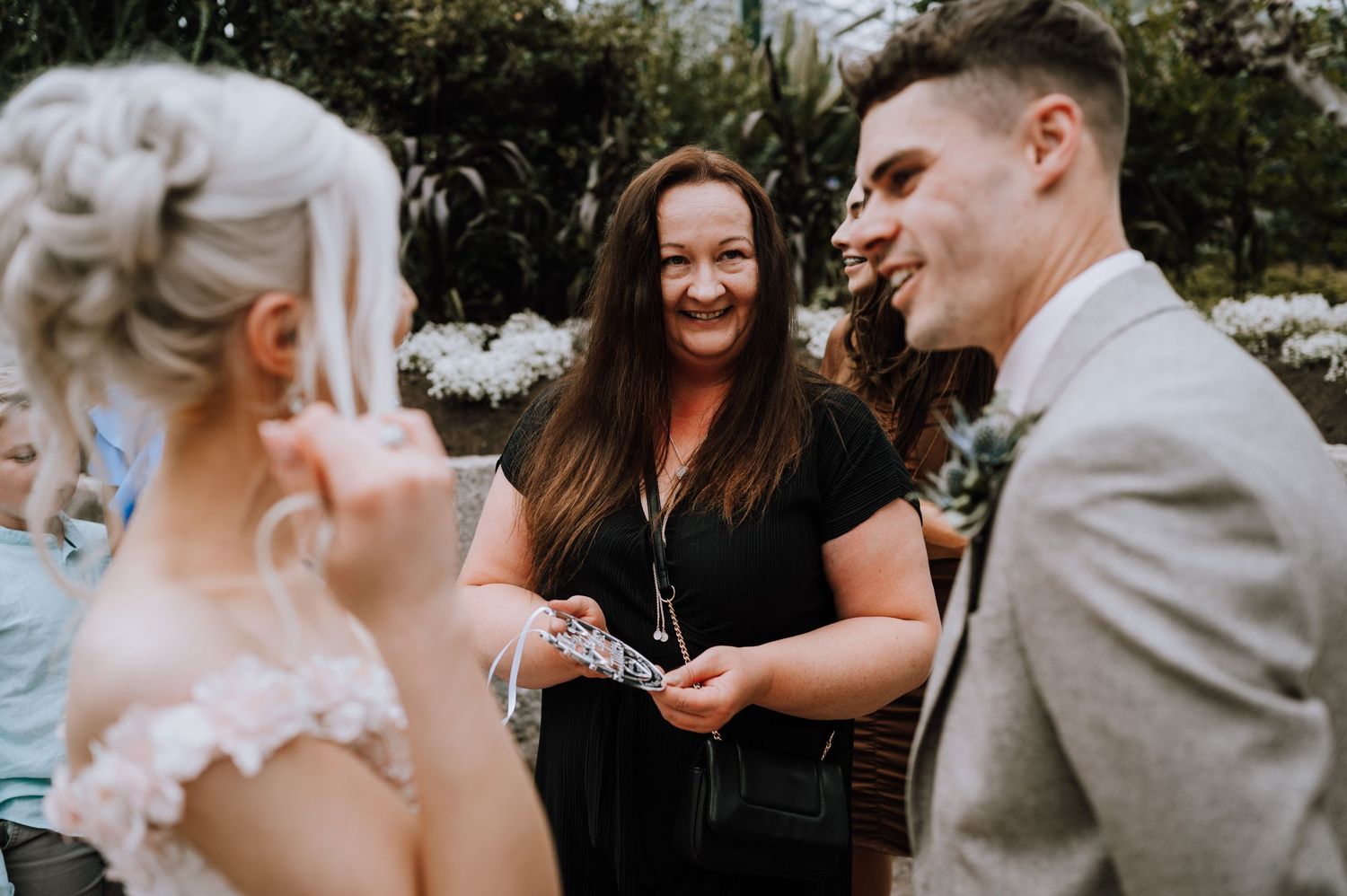 Wedding guests gather for a cheerful moment during an outdoor garden ceremony.