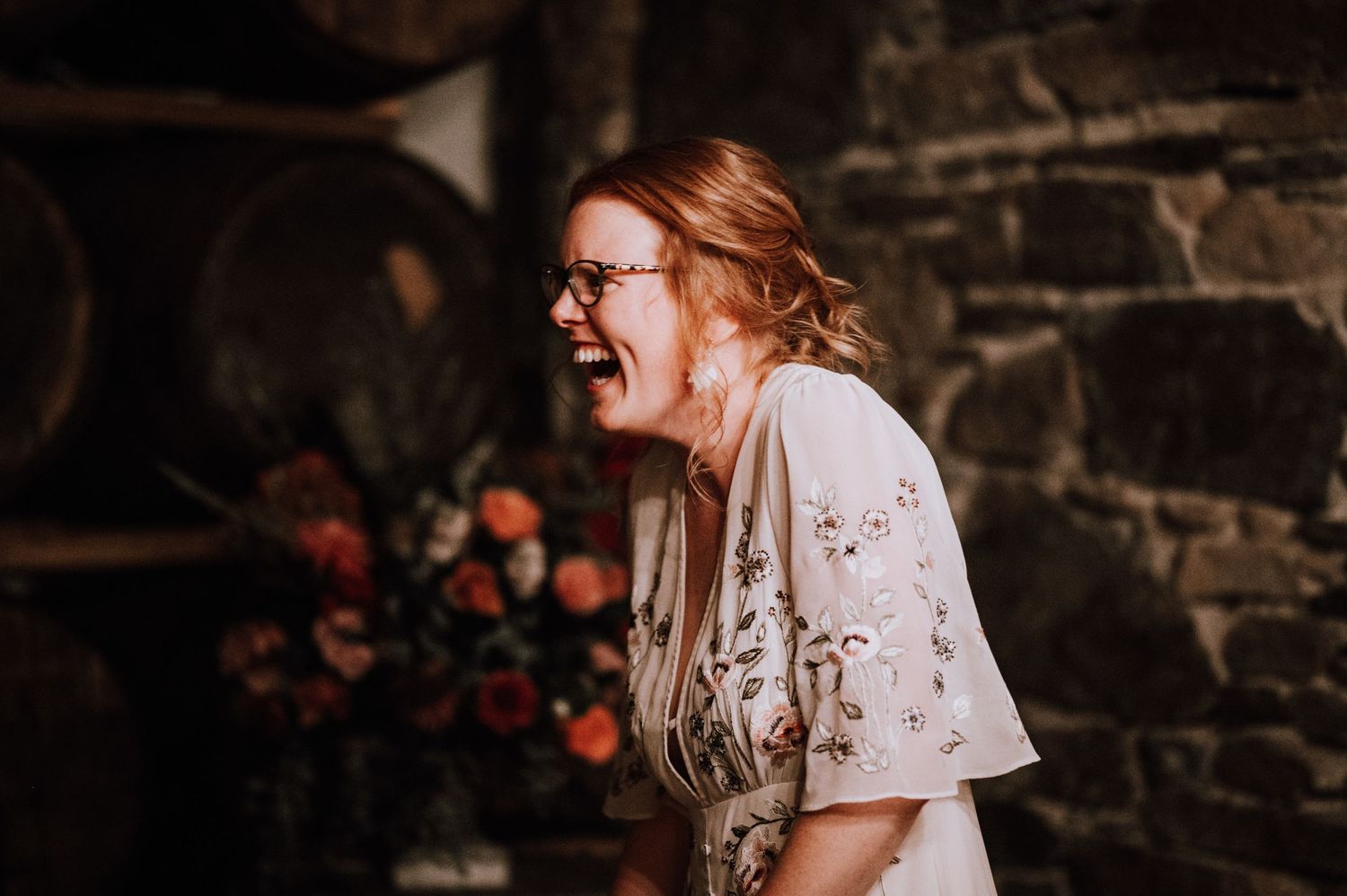 Candid moment of joy captured against stone walls and floral decorations.