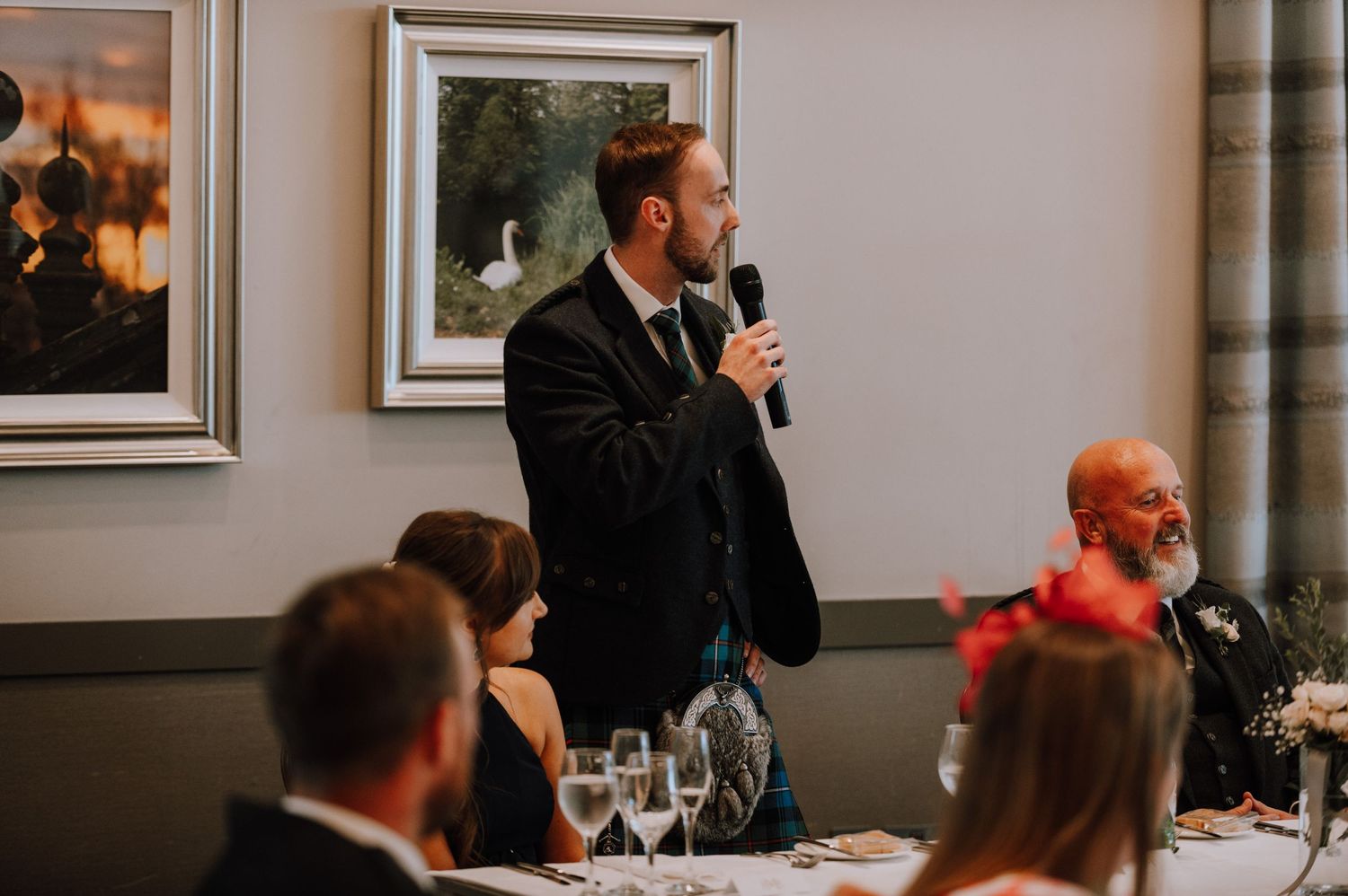 A speaker delivers a wedding speech at an elegant indoor reception.