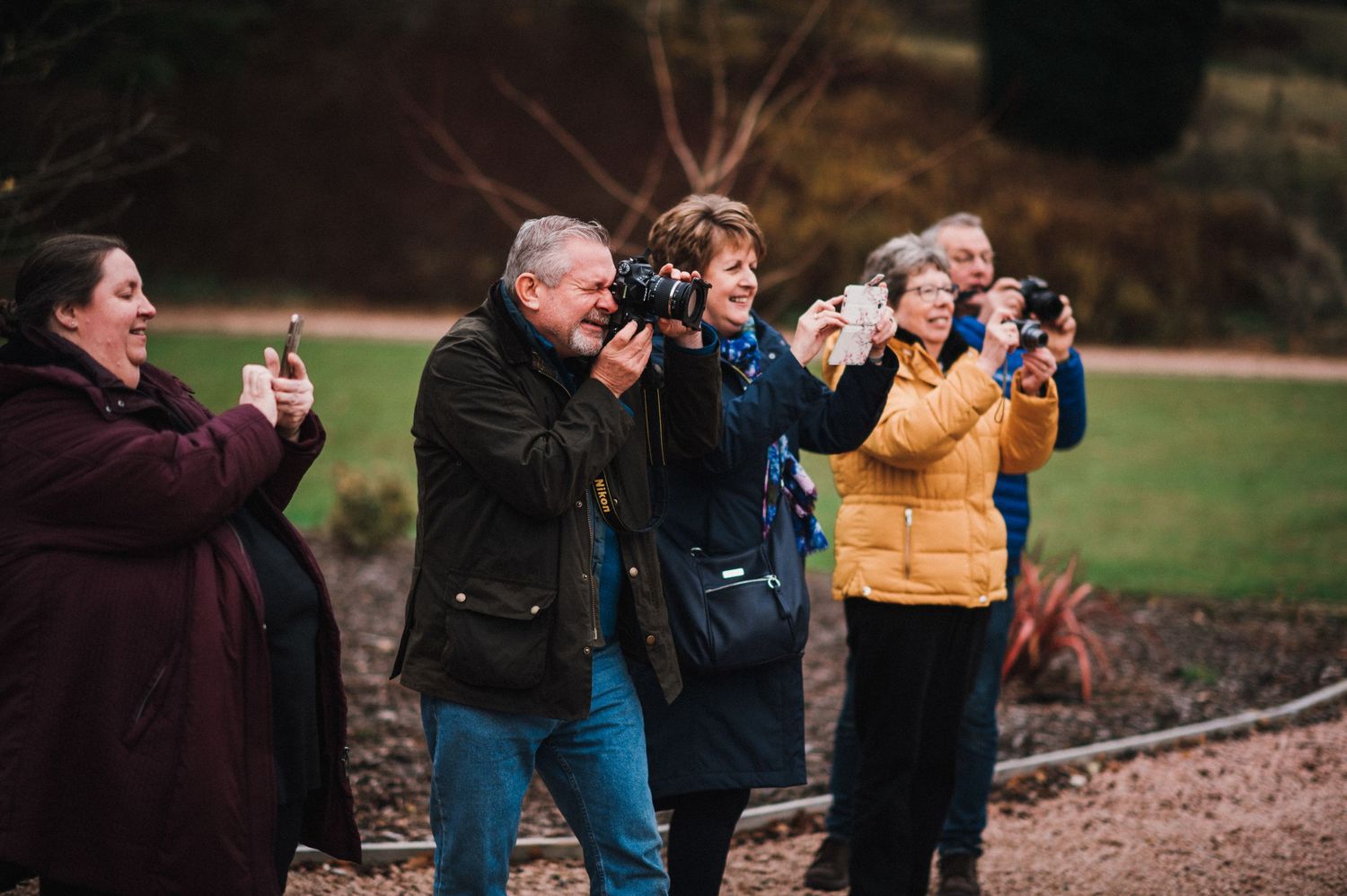 Group of photographers capturing moments at outdoor wedding event.