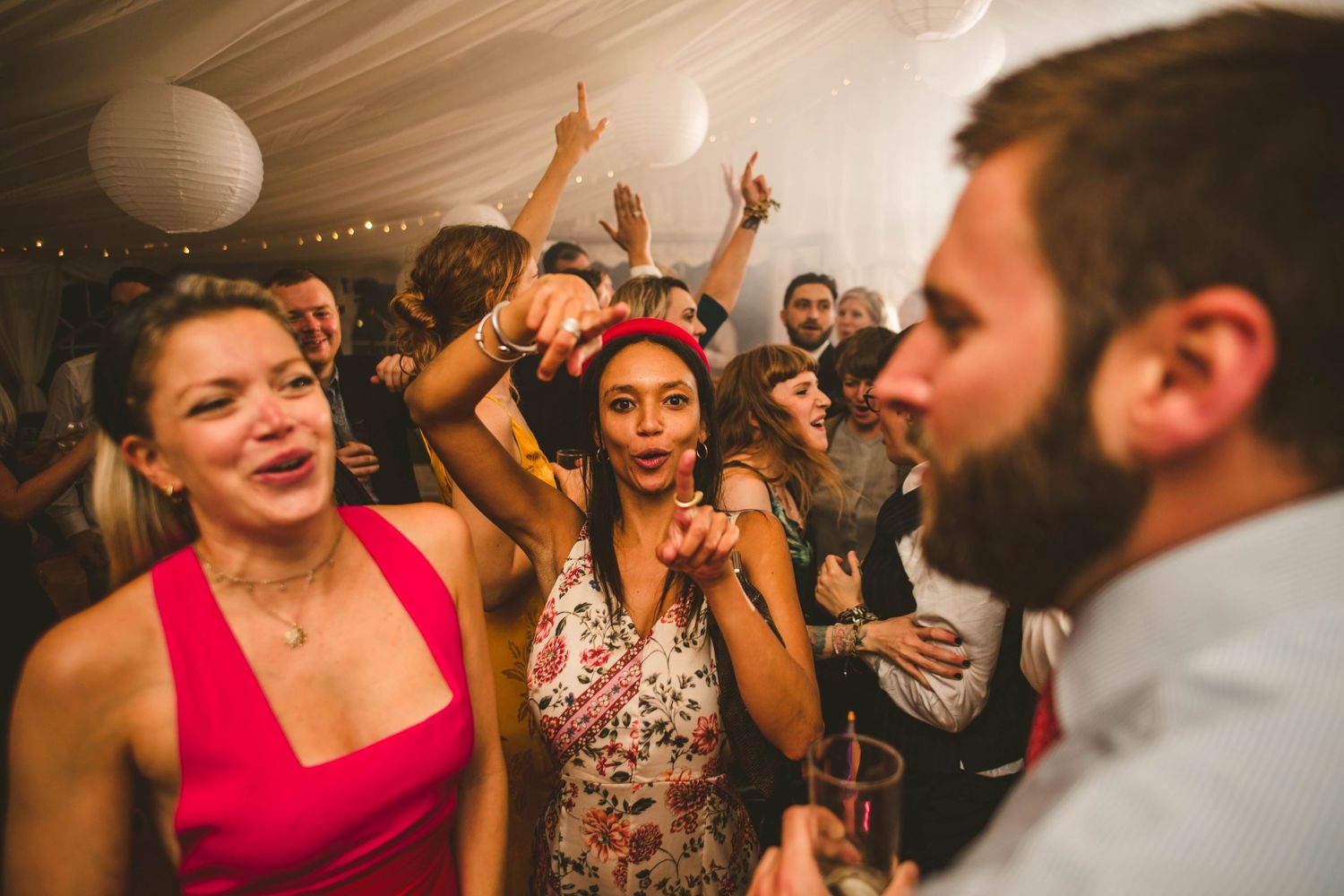 Wedding guests dancing enthusiastically at a lively reception party.
