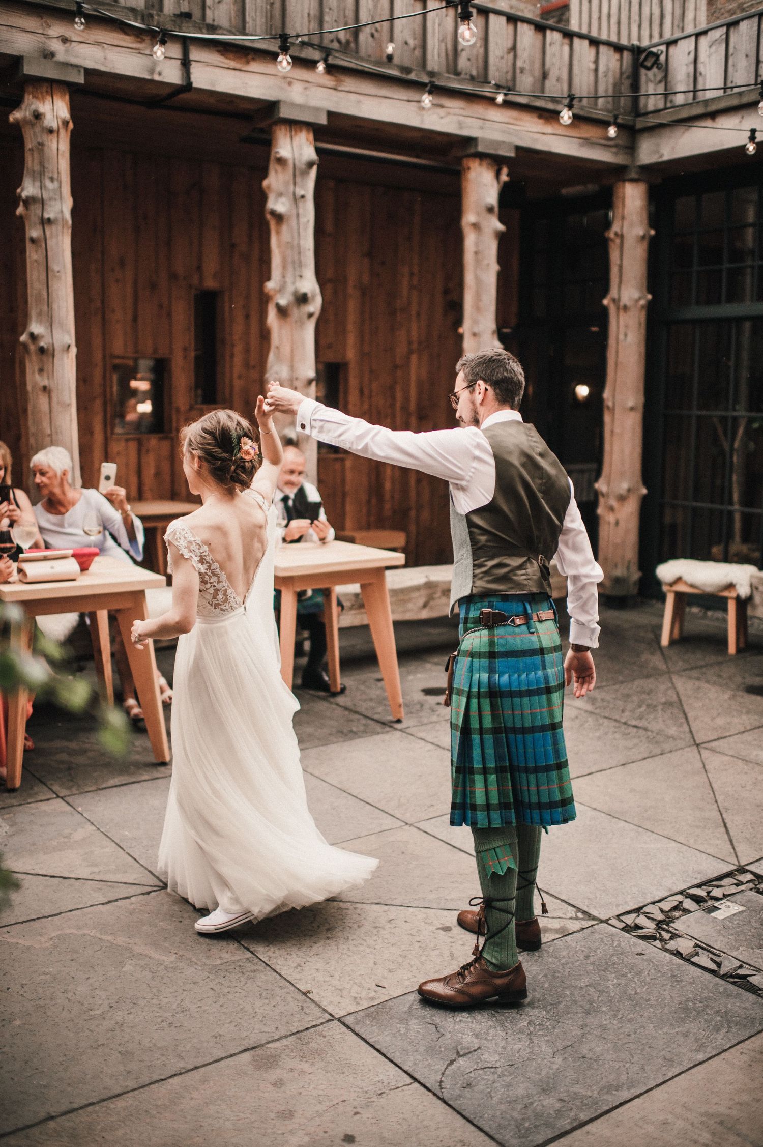 Traditional Scottish wedding dance with kilted attire in historic stone courtyard.