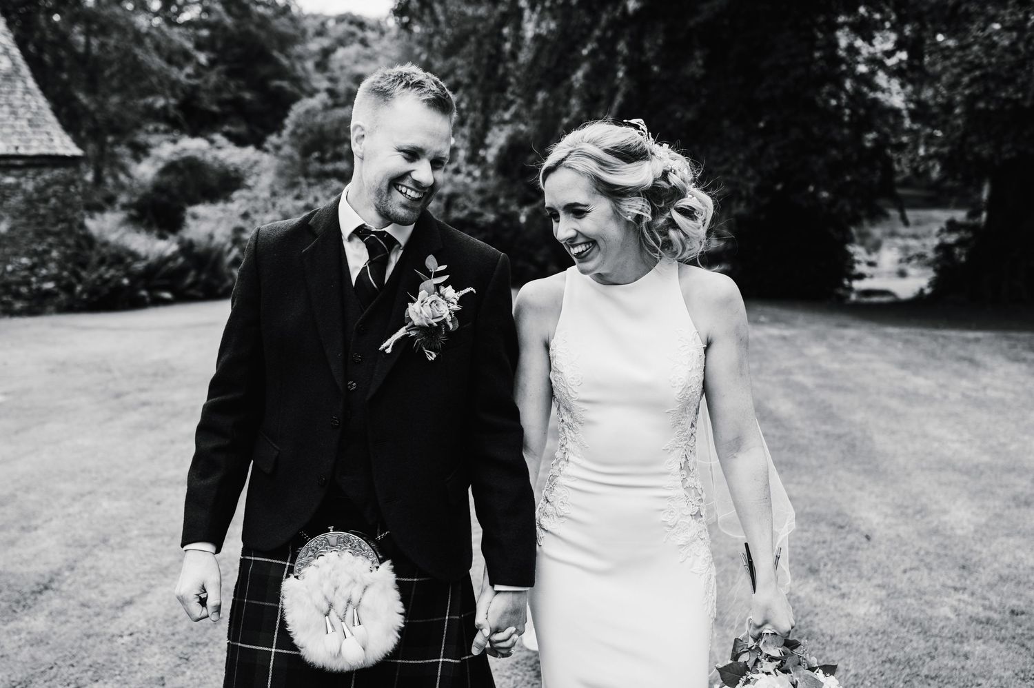 Candid black and white moment of couple sharing laughter in garden setting.