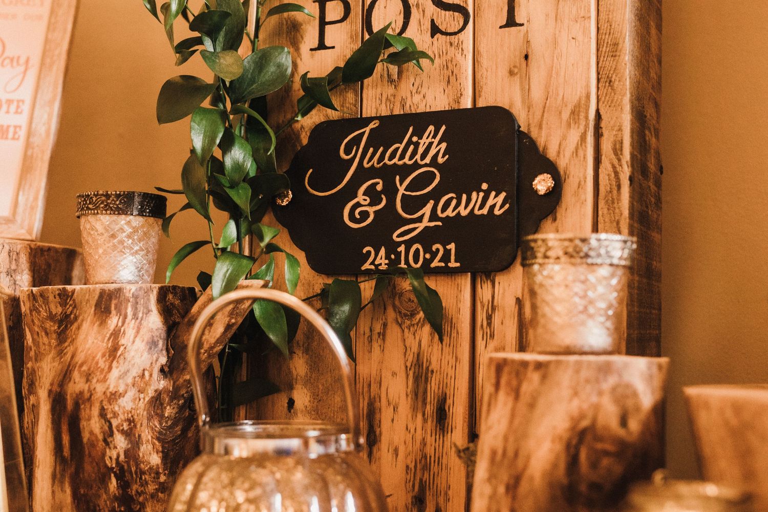 Wooden wedding post box decorated with greenery and candles displaying couple's date.