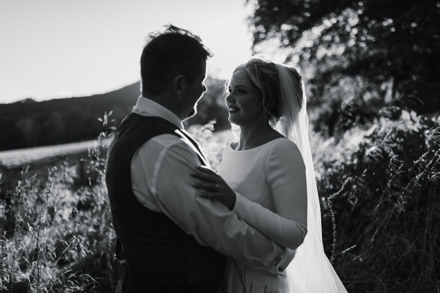 Black and white portrait of couple sharing intimate moment during outdoor wedding.