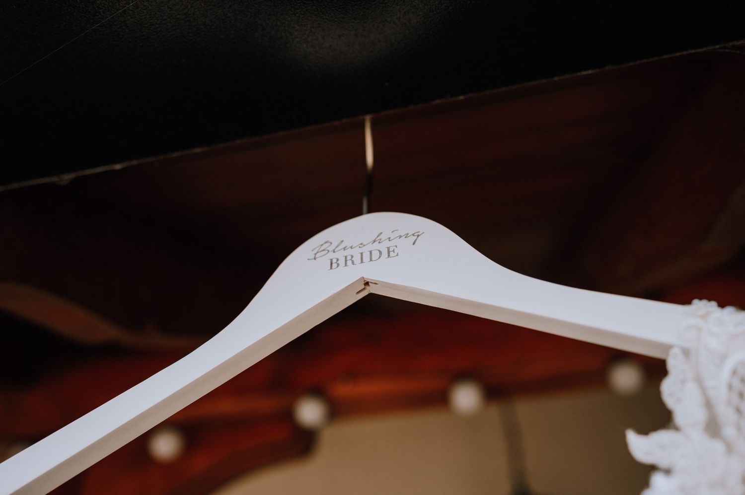 A white wooden wedding dress hanger with custom text.