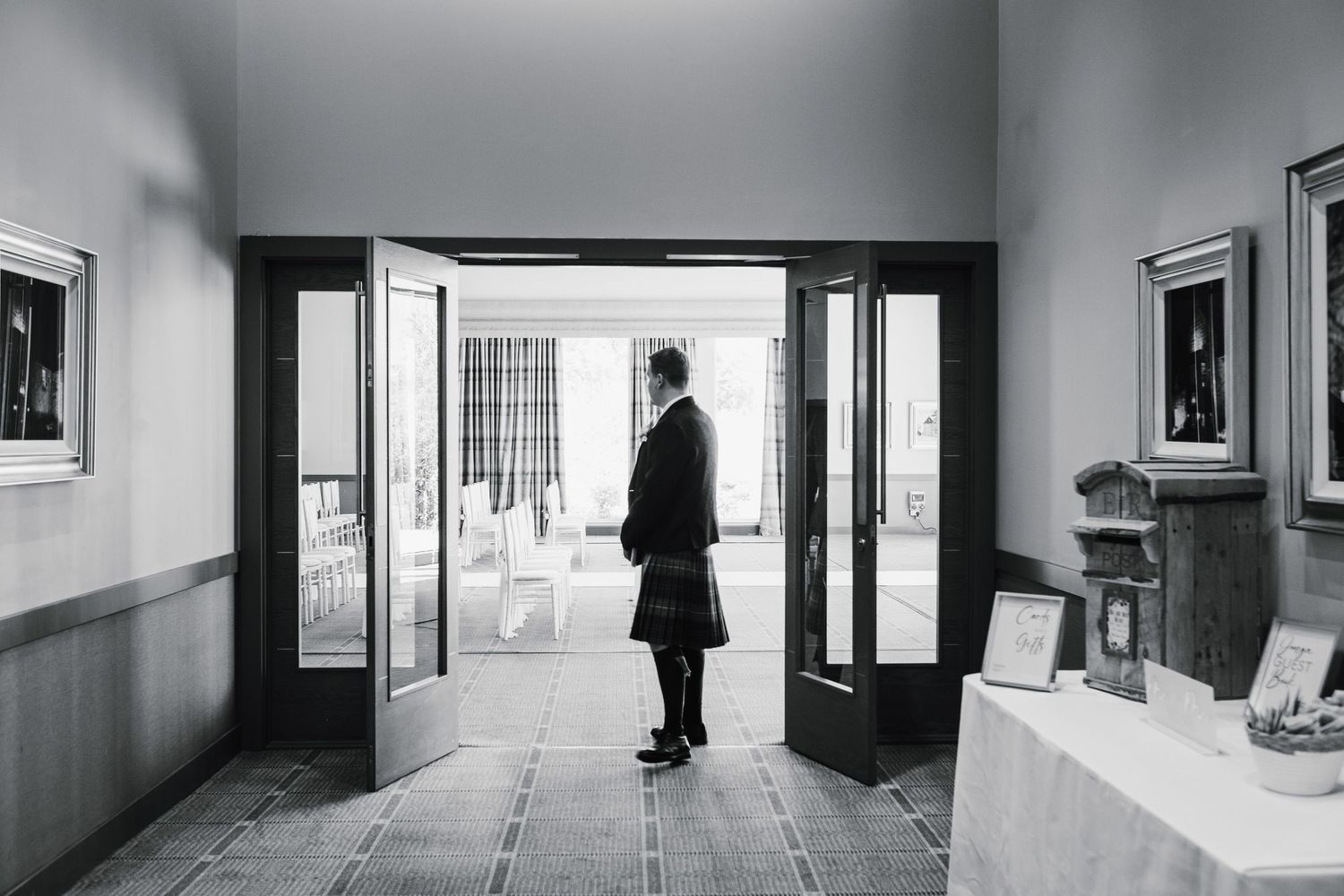 Black and white photo of silhouette in formal attire standing in doorway.
