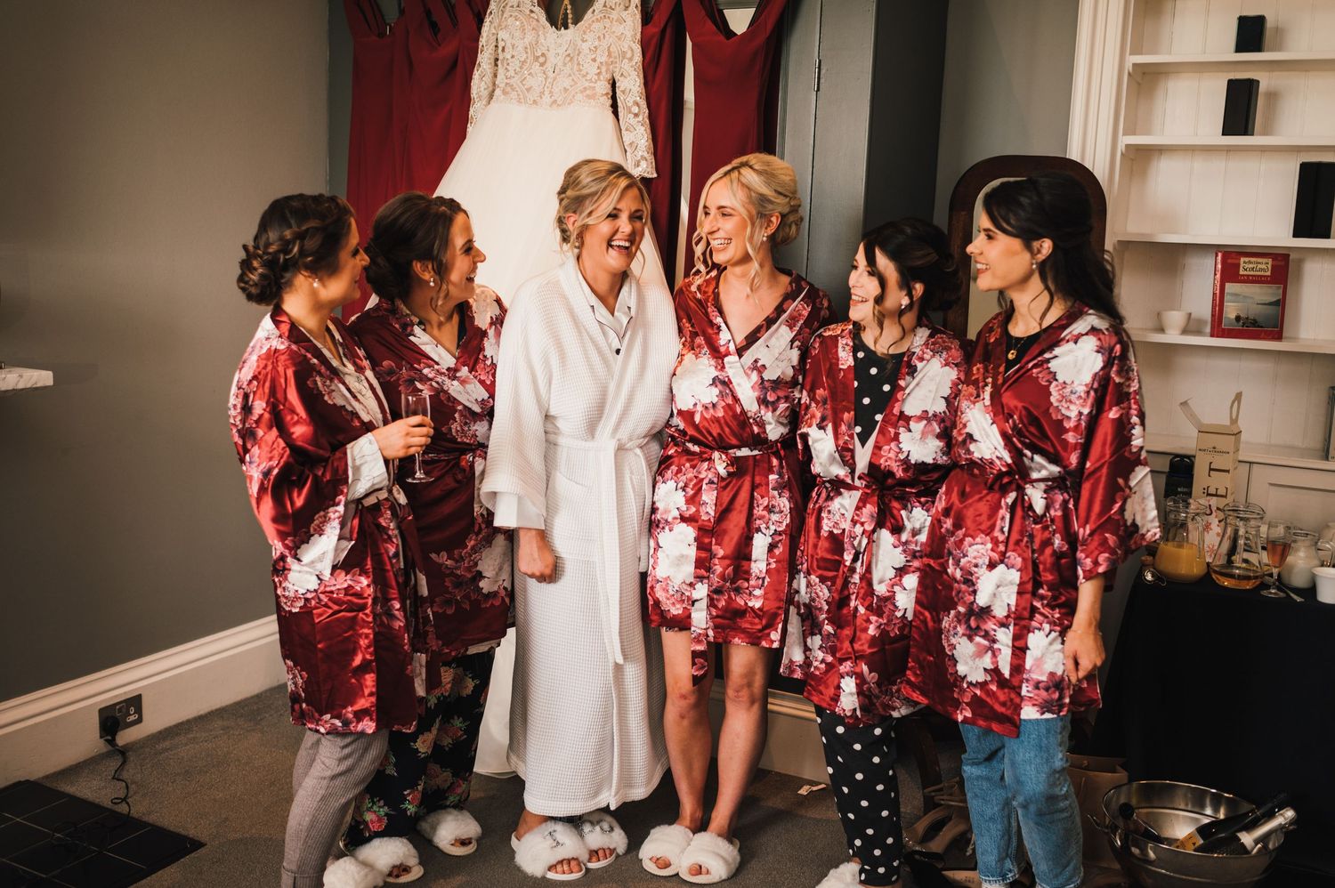 A group wearing matching floral robes gather together during wedding preparations.