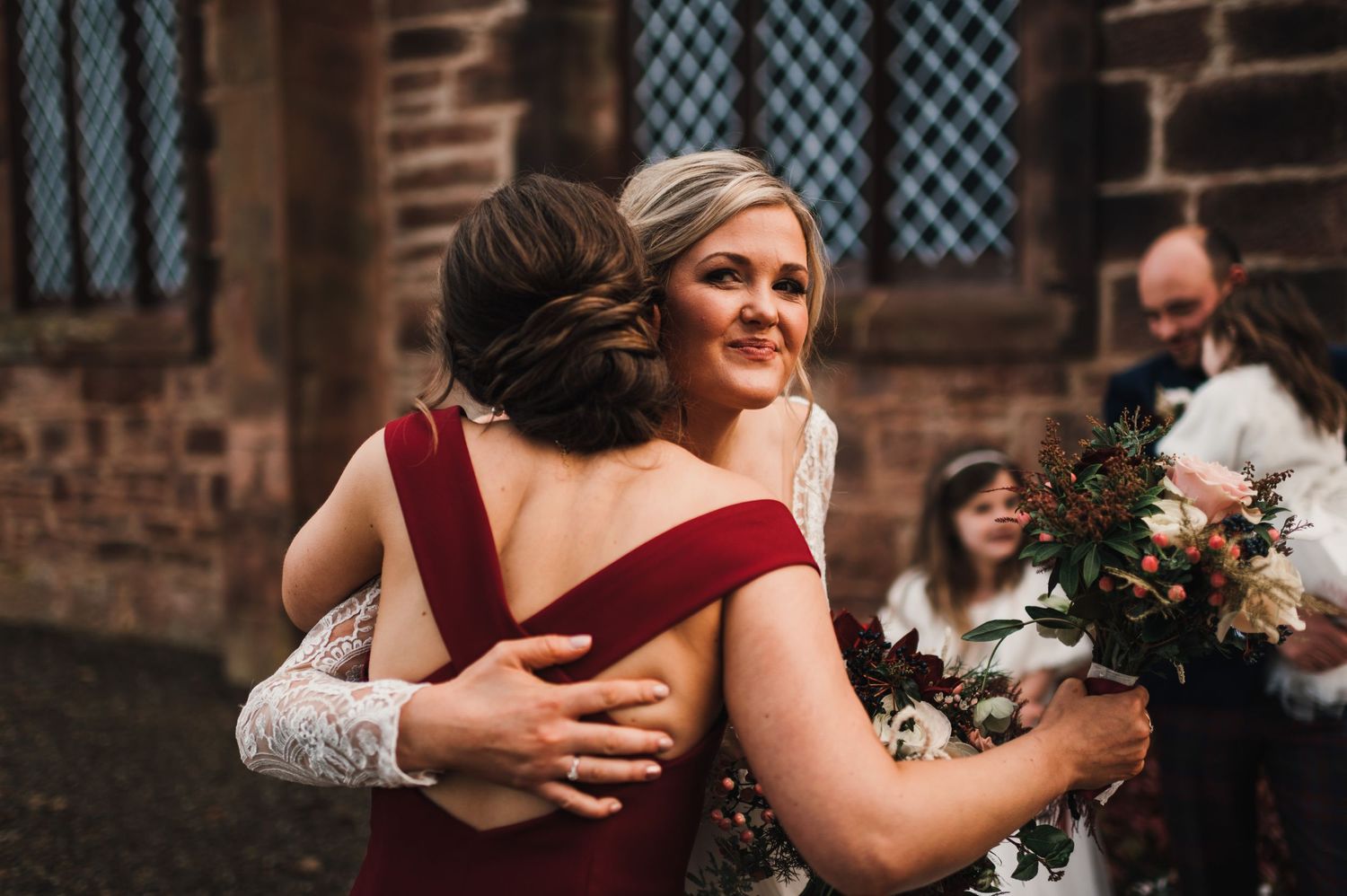 Joyful wedding celebration moment outside historic brick church with Gothic windows.