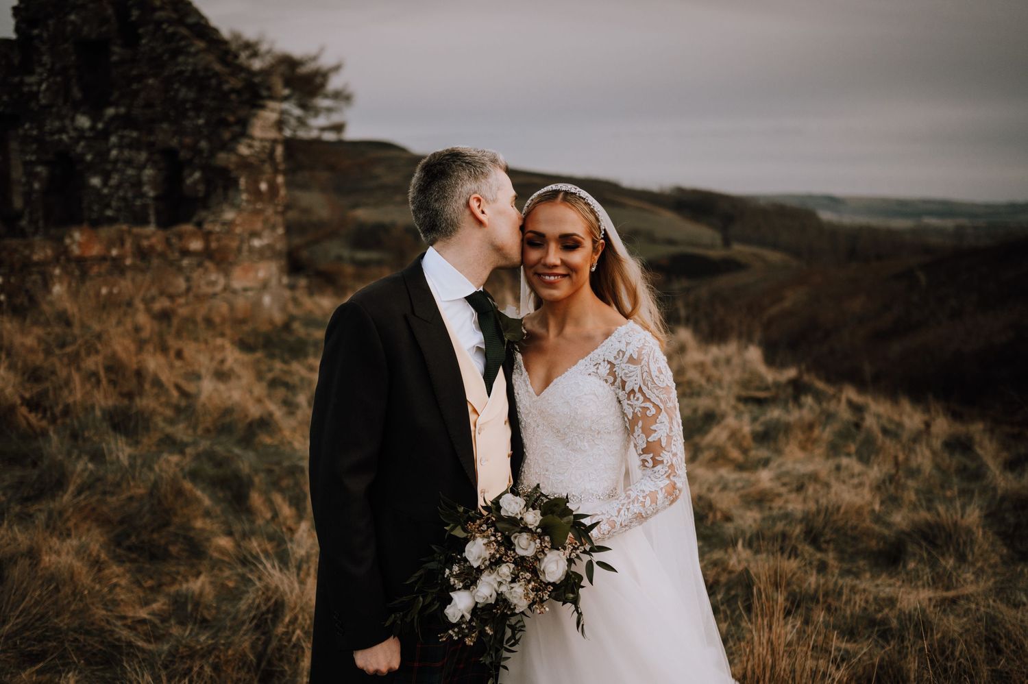 Intimate wedding moment captured against scenic highland landscape.