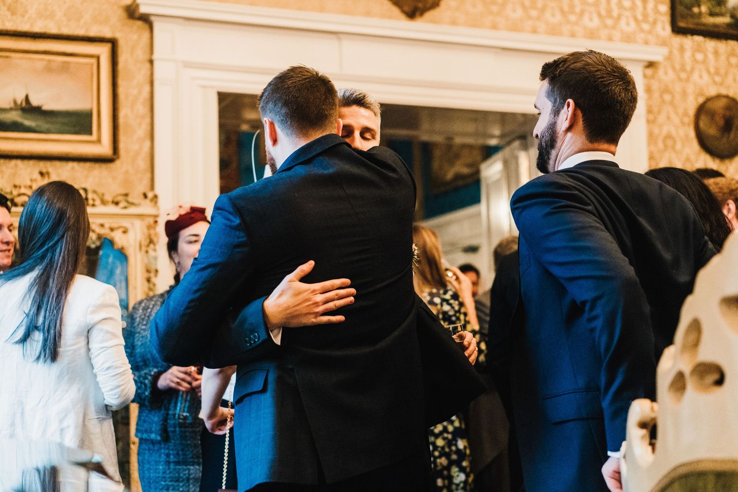 Wedding guests embrace and celebrate during a reception in an elegant indoor setting.