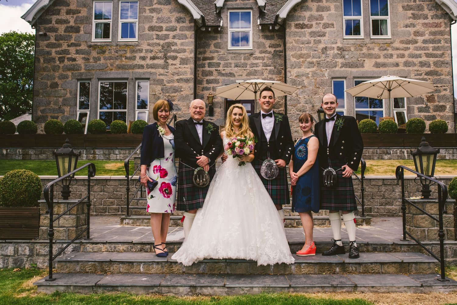 Stone building wedding venue with guests gathered on outdoor steps.