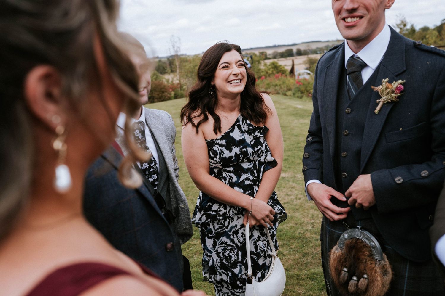 Wedding guests sharing laughs during outdoor reception.