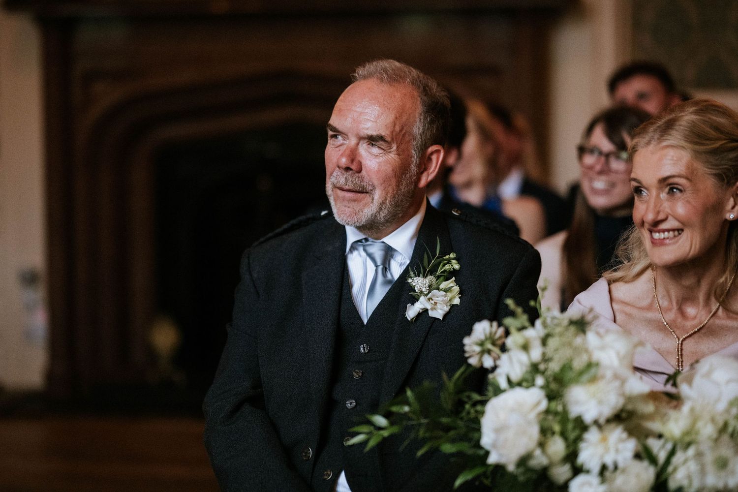 Wedding ceremony attendees watch emotionally from wooden pews in an elegant church setting.