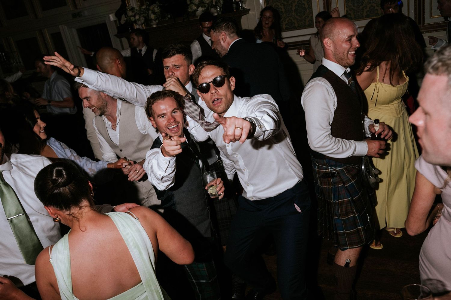 Energetic group of wedding guests dancing and having fun at a reception party.