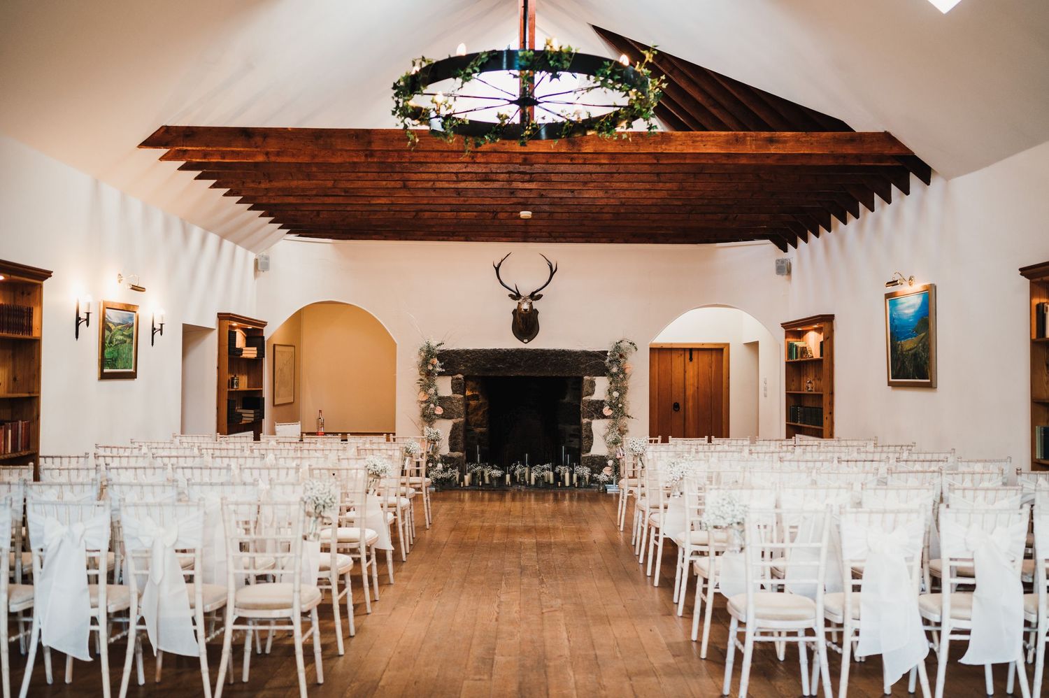 Wide panoramic view of a rustic wedding venue with wooden beams and white chairs set up for a ceremony.