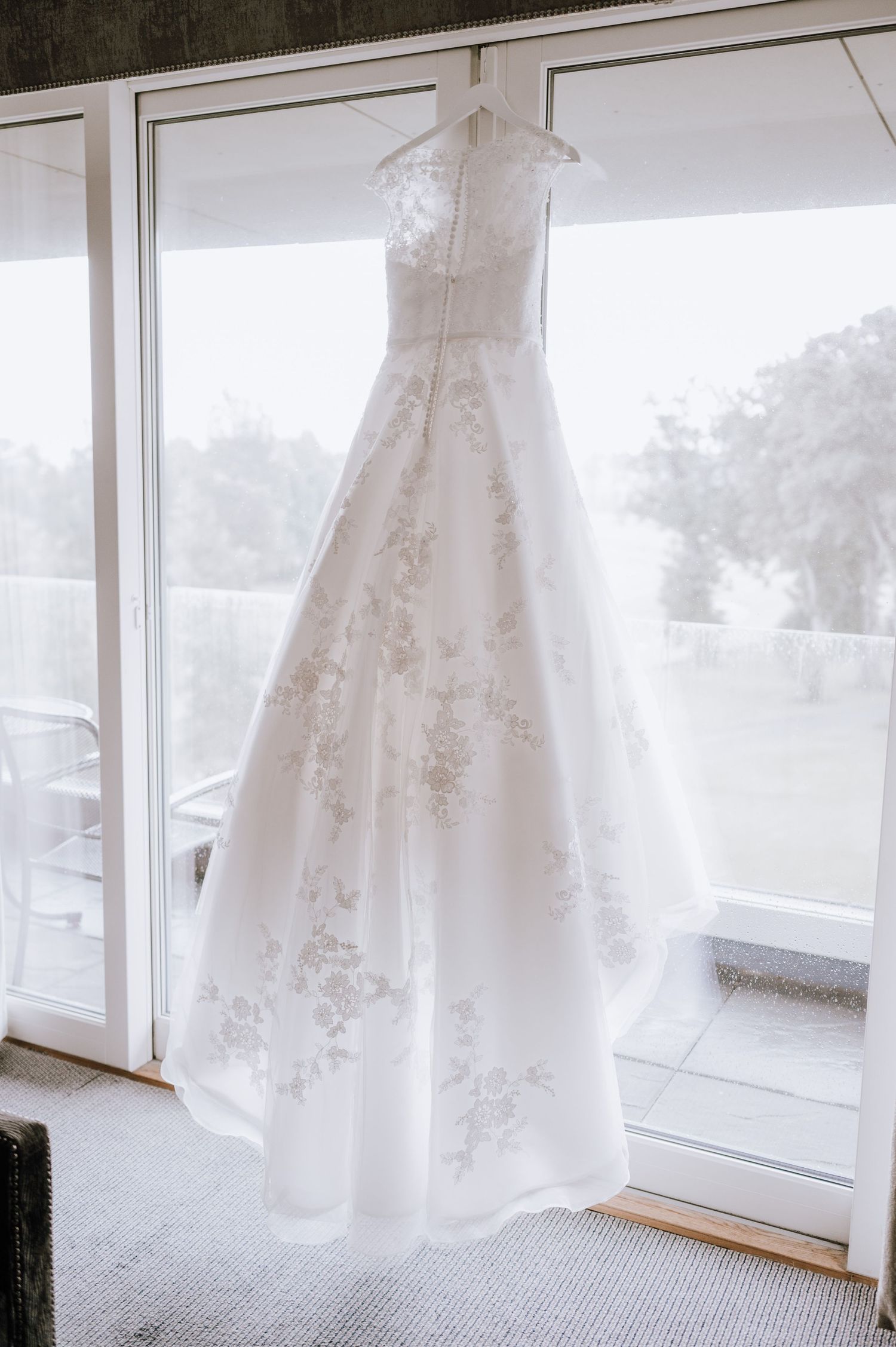 Meldrum House Wedding Photography. White wedding dresses hanging by large windows in natural light.