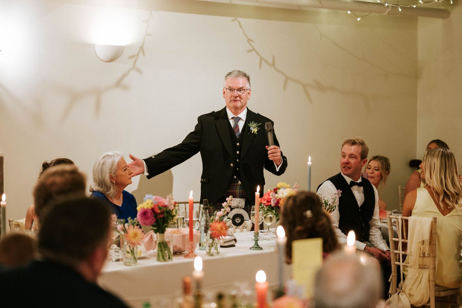 Formal dinner reception with guests seated at decorated tables in an elegant banquet hall.
