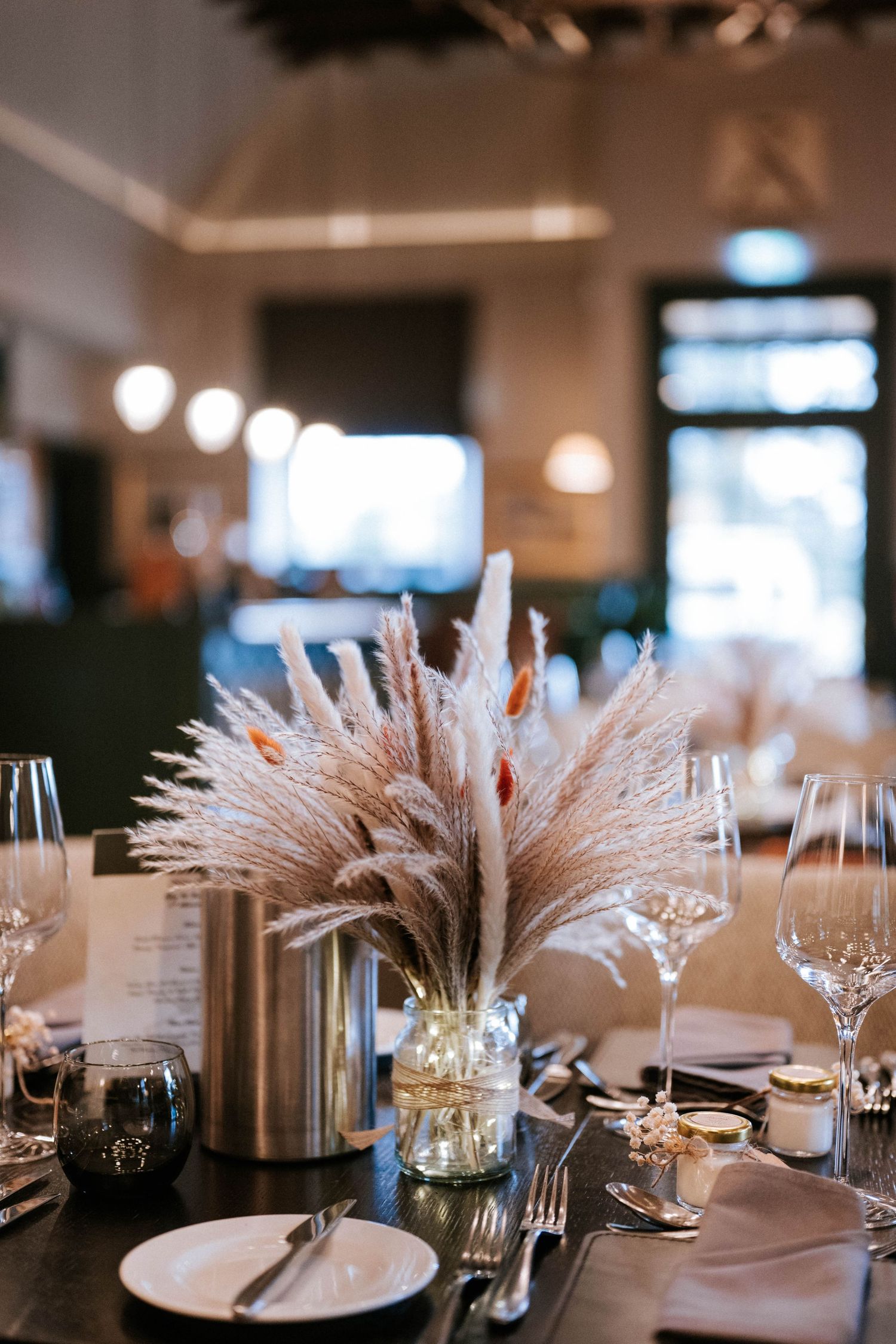 Elegant wedding table settings with white pampas grass centerpieces and crystal glassware.