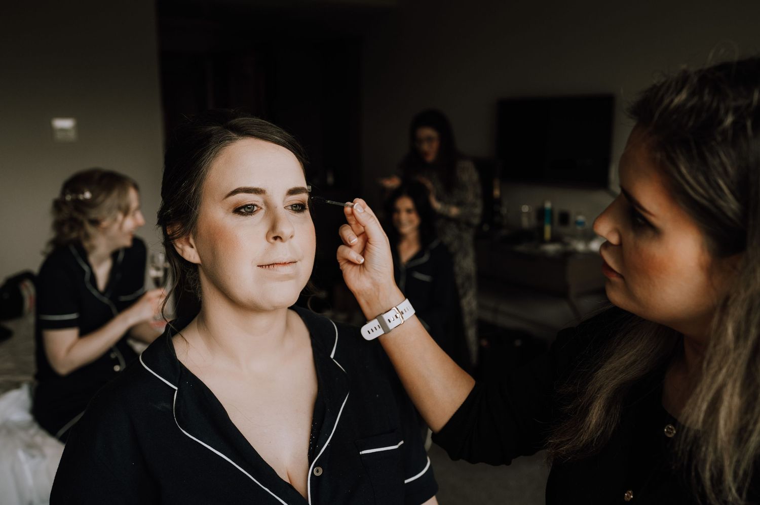 Wedding party members getting hair and makeup done in dark room Meldrum House Wedding Photography.