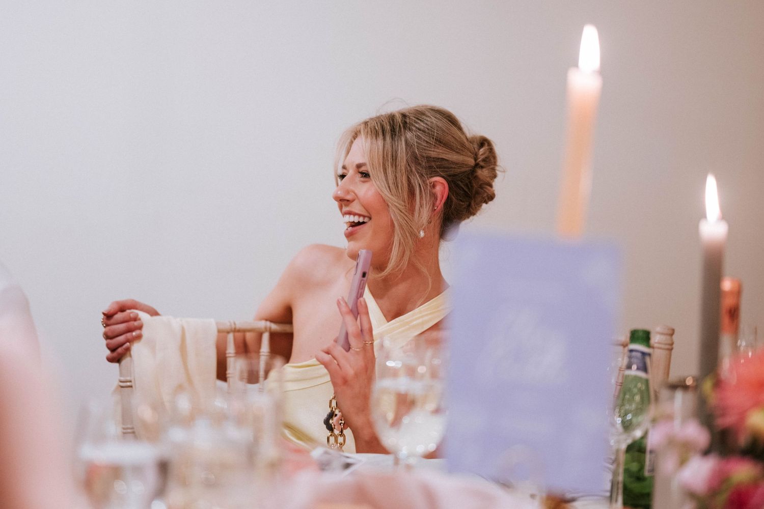 Candlelit wedding reception tables with laughter and joy during dinner service.