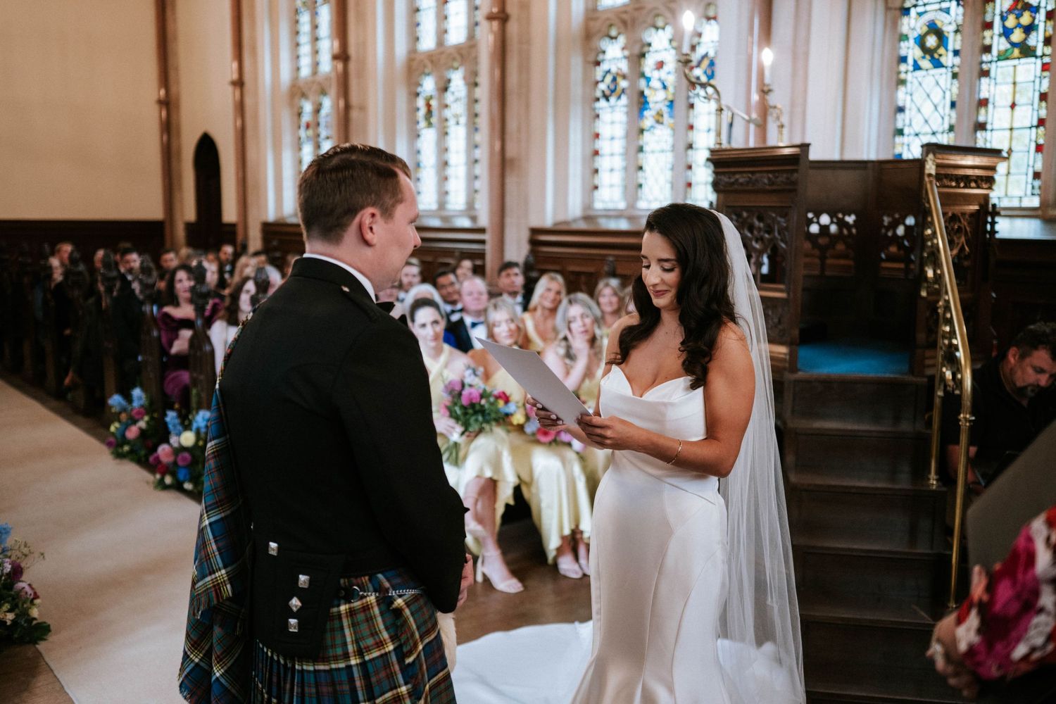 Wedding ceremony in progress inside a beautiful church with stained glass windows.