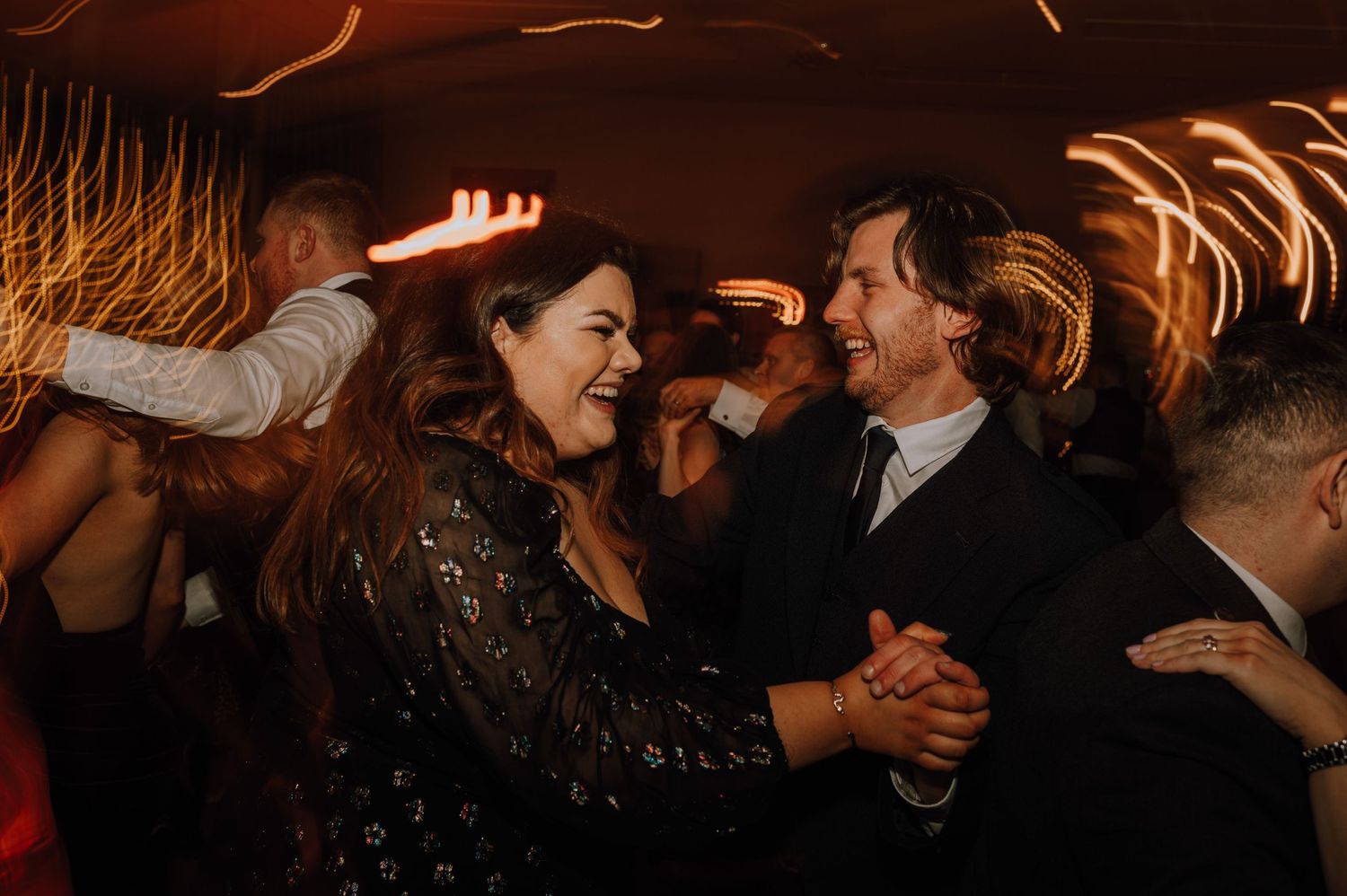 Joyful couples dancing and laughing together at a lively wedding reception.
