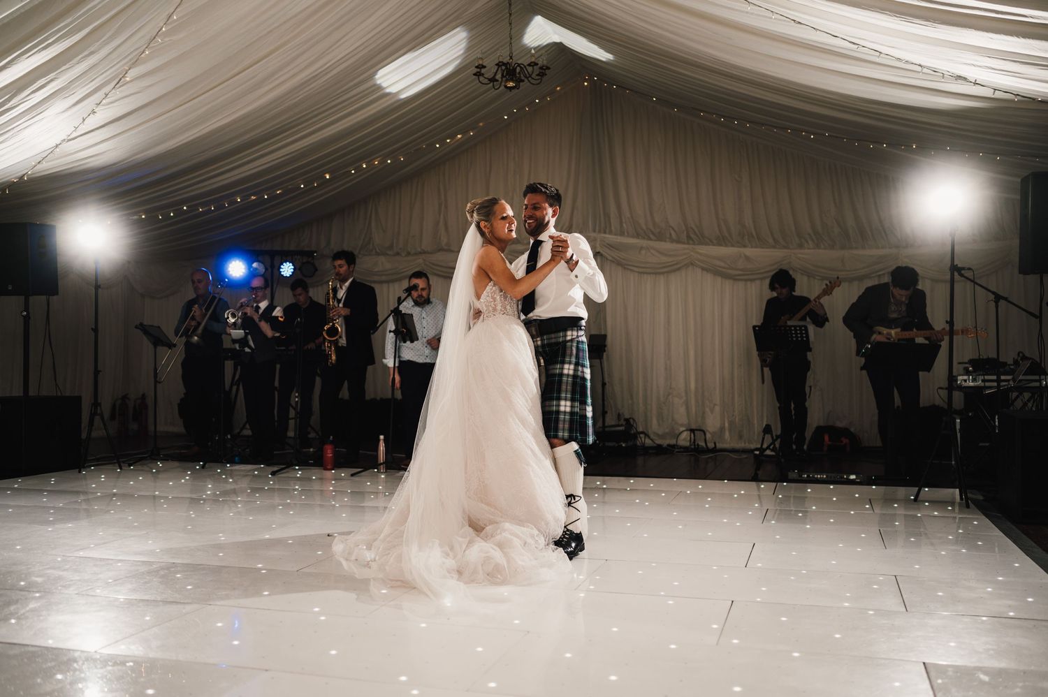 A romantic first dance moment captured in an elegantly decorated wedding reception marquee.