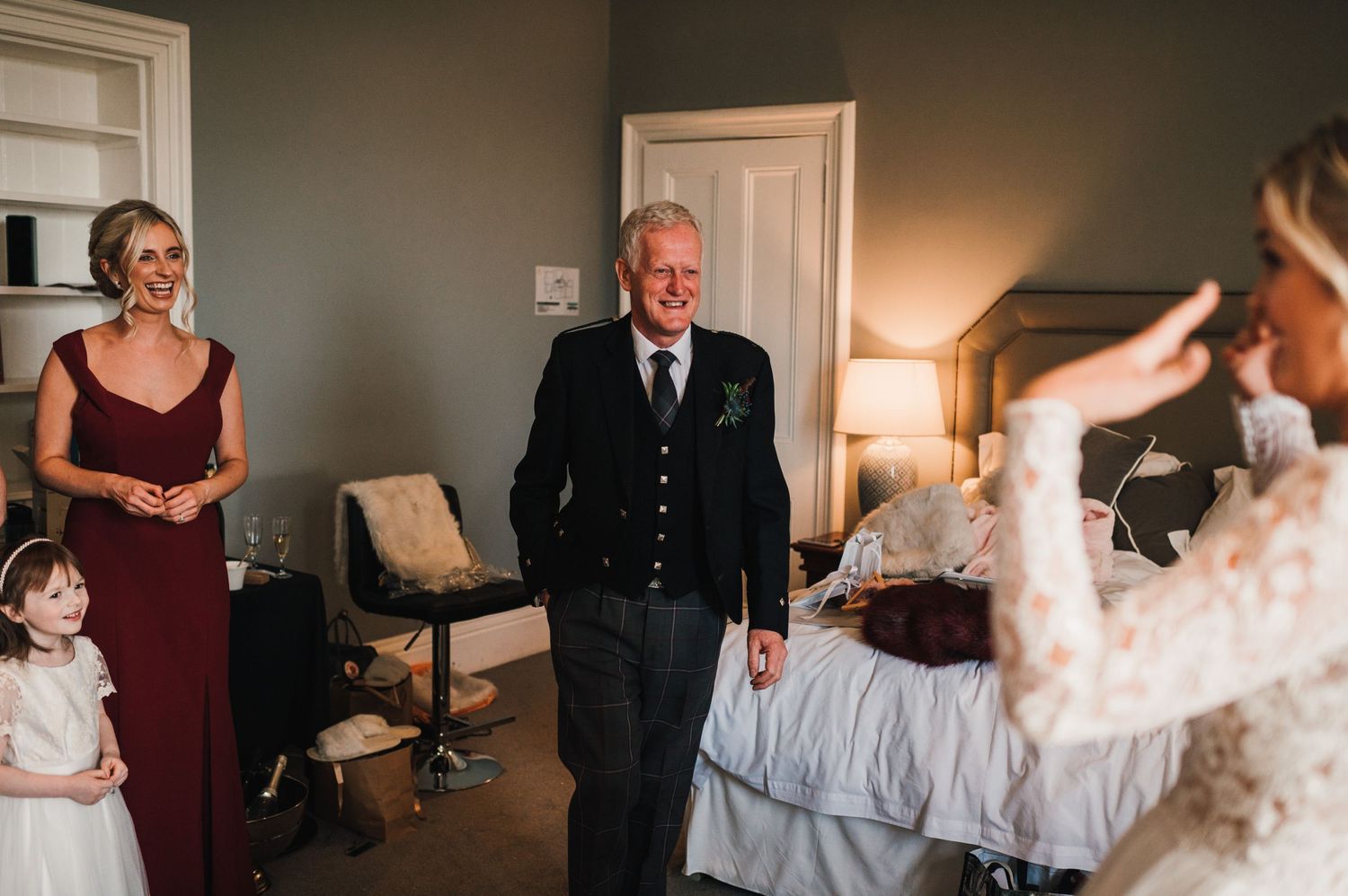 An emotional moment unfolds during wedding preparations in a softly lit room.