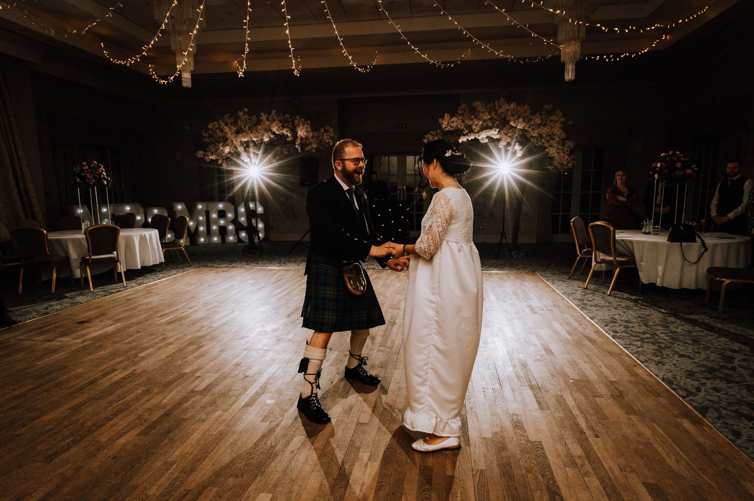 Traditional Scottish and Japanese fusion wedding dance on wooden ballroom floor.
