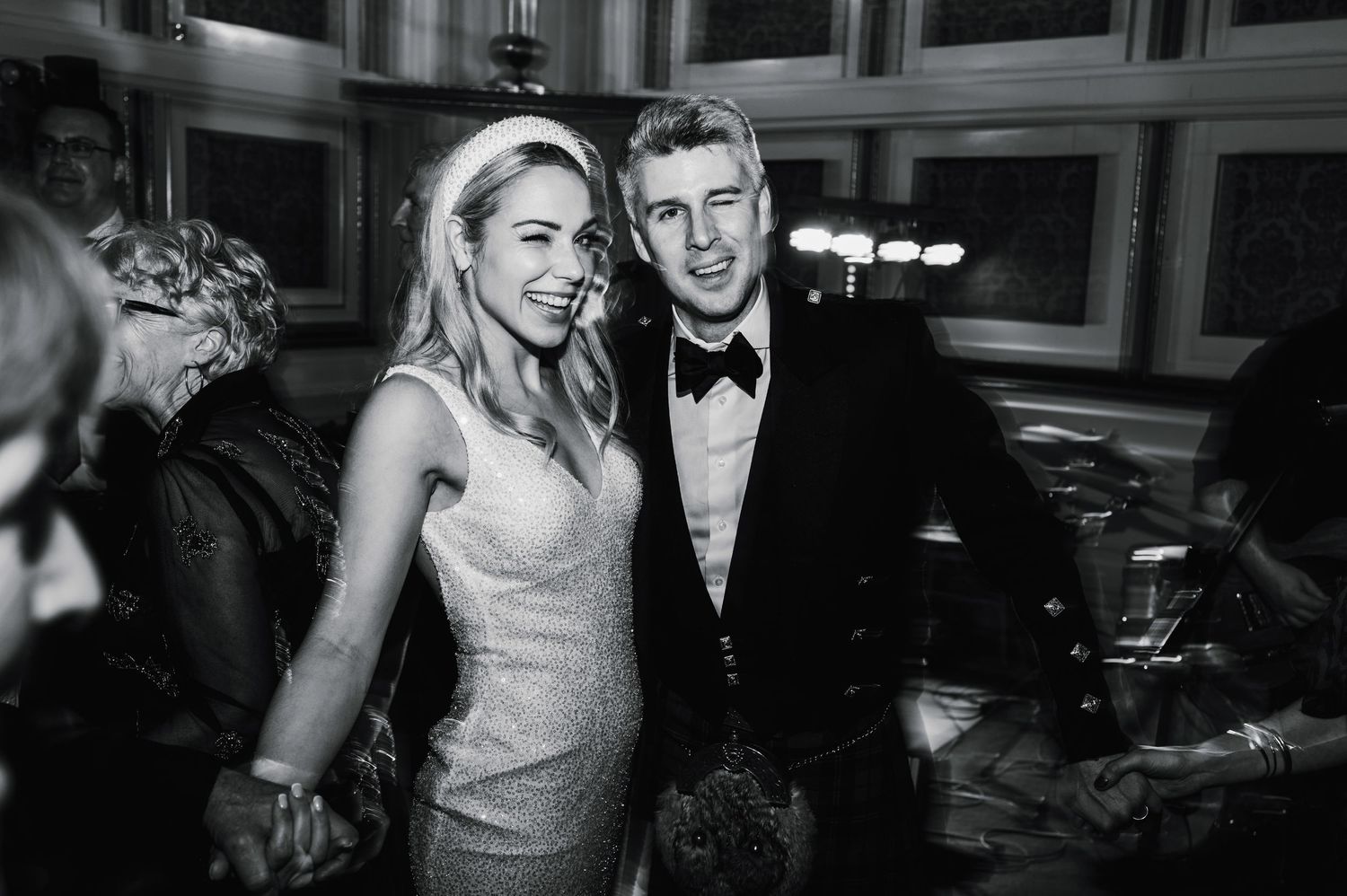 Black and white photo of a glamorous couple at an elegant evening wedding celebration.