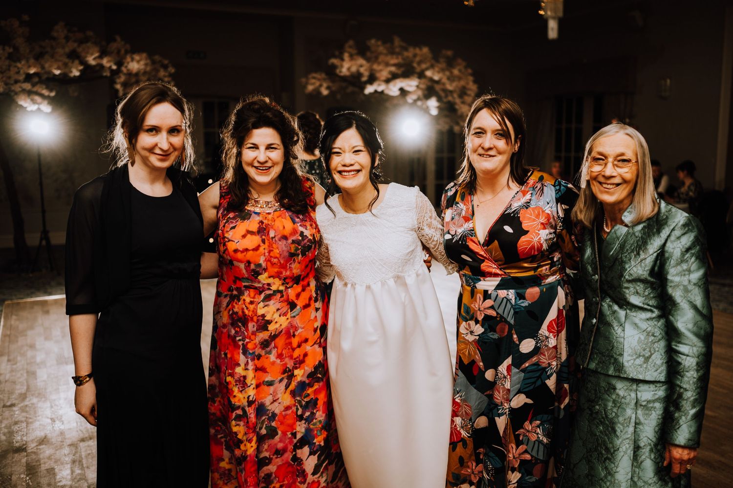 Group photo of friends in colorful formal dresses at an evening celebration.