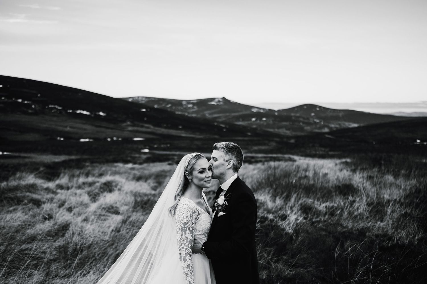Black and white wedding portrait in windswept mountainous terrain.