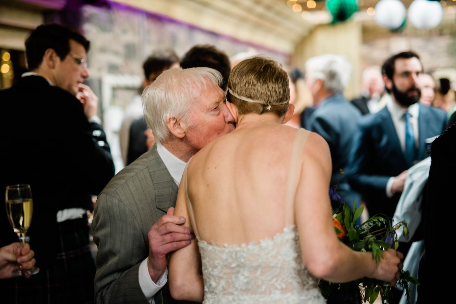 Intimate moment during wedding reception with backless dress and champagne glasses.