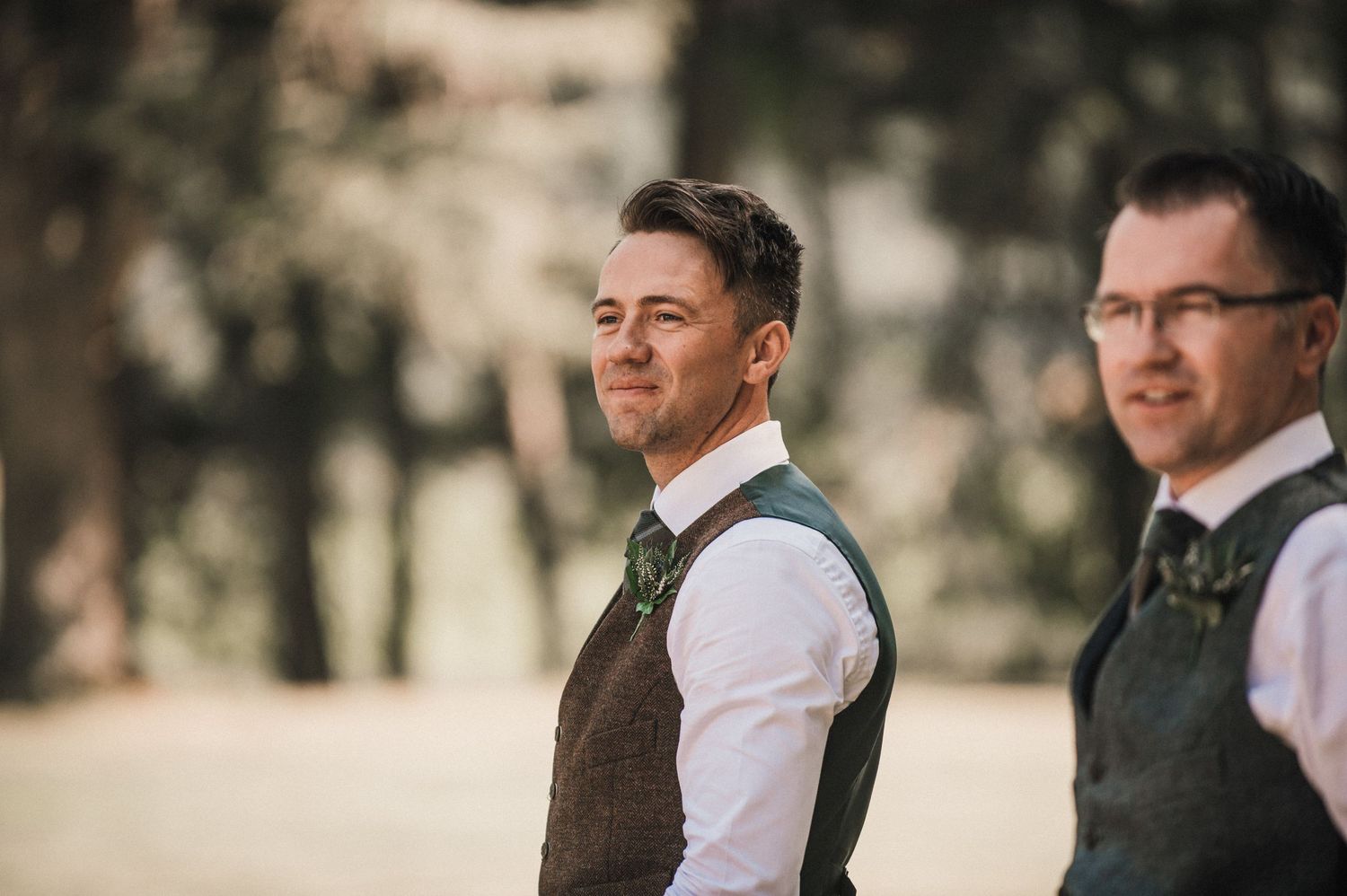 Groomsmen in traditional vests stand outdoors during wedding celebration.