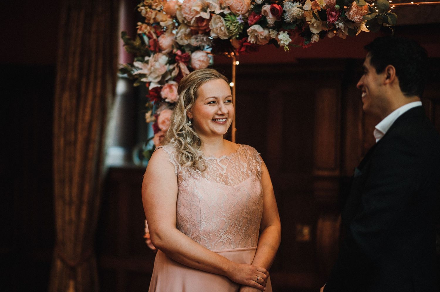 A joyful moment captured during an indoor wedding ceremony beneath floral decorations.