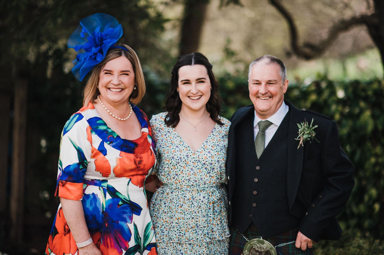 Wedding party members dressed in formal attire posing outdoors.
