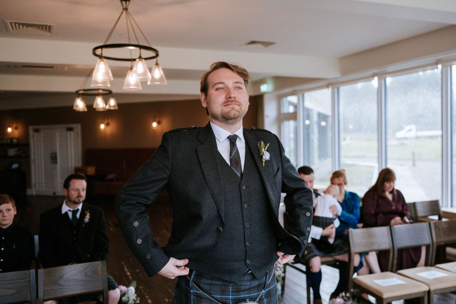 Wedding celebration in a bright venue with chandelier lighting and scenic window views.