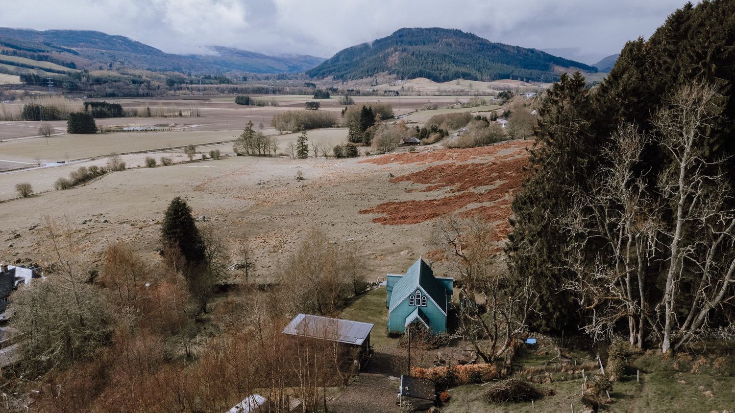 A charming blue A-frame house situated in a scenic mountain valley.