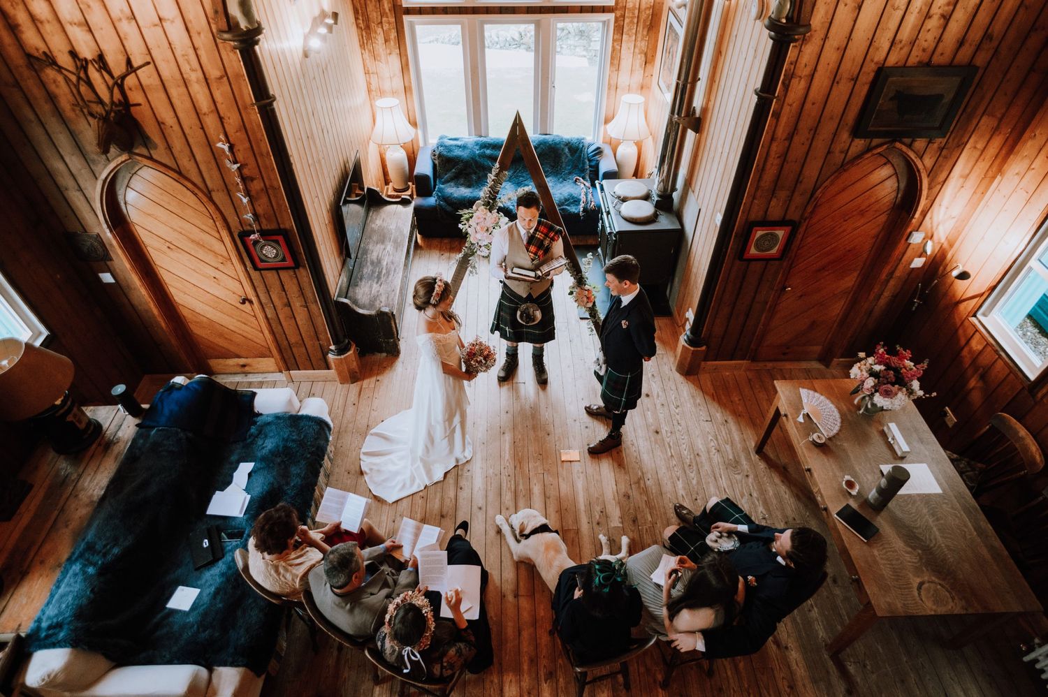 Overhead view of a wedding ceremony in a rustic wooden room with natural lighting.