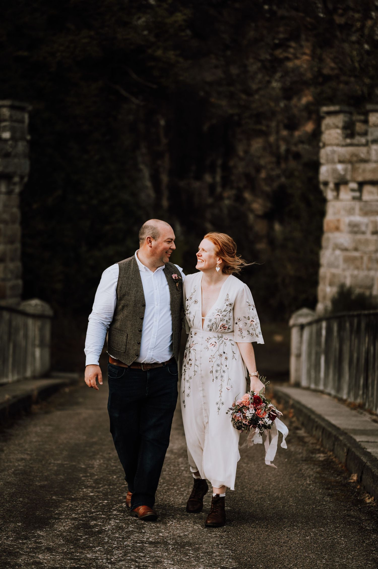 A couple walking together on a stone bridge path during their wedding day.