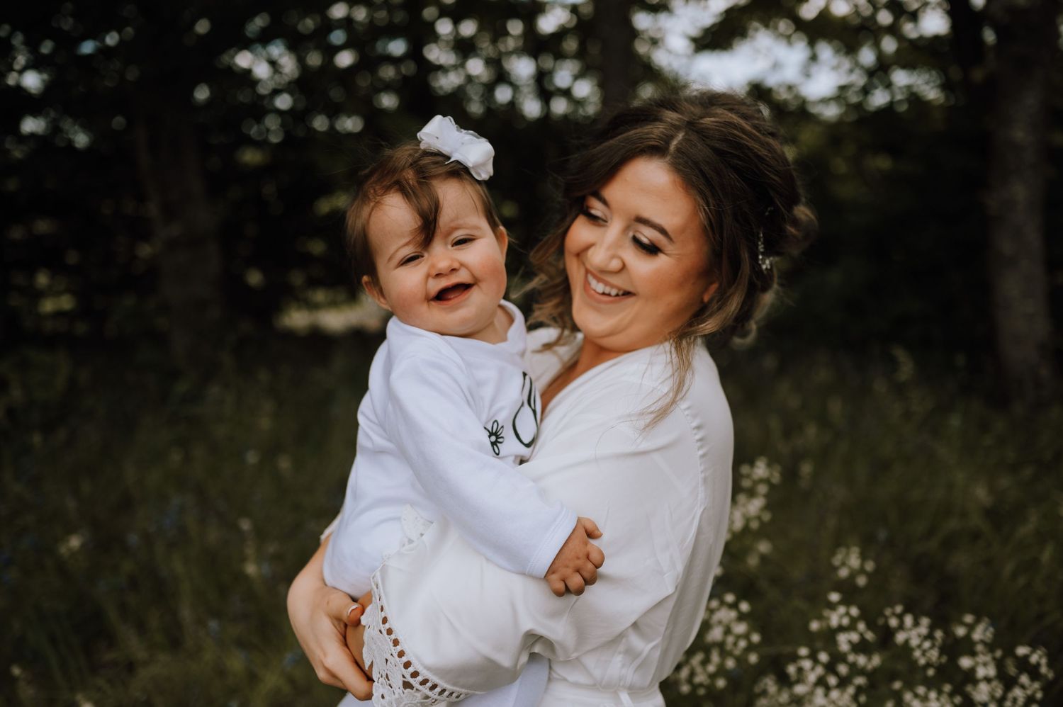 A joyful moment captured between two figures in white robes embracing outdoors.