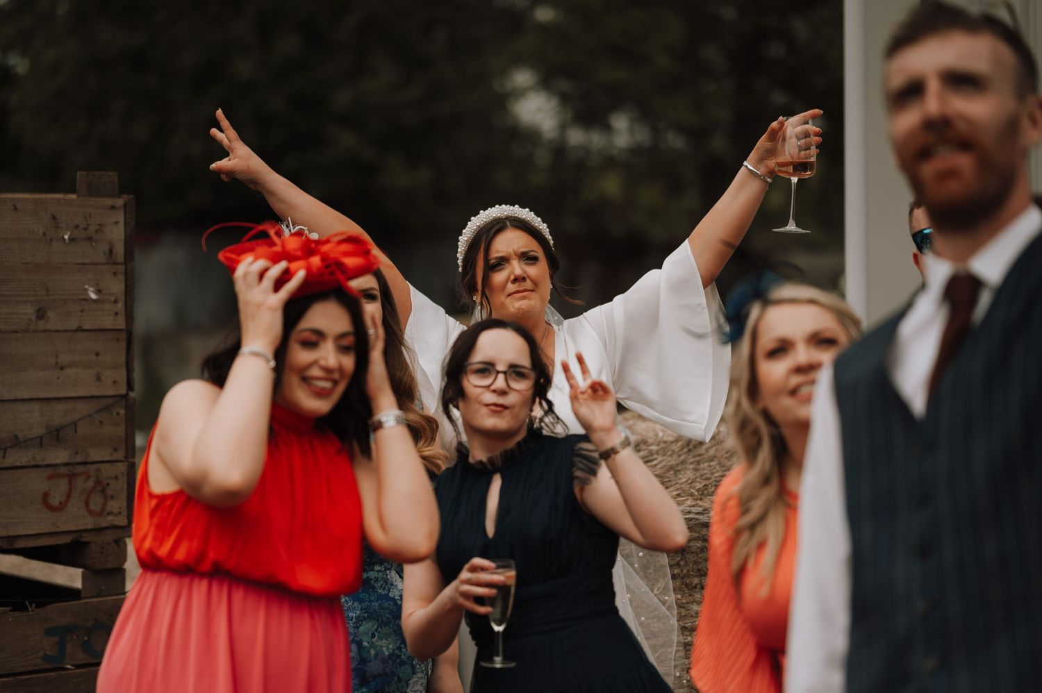Wedding party celebrates with drinks and laughter outdoors.