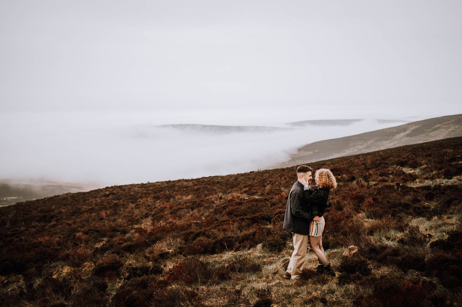 Engagement photography session Aberdeen. Misty mountains and moorland create a dramatic landscape under cloudy skies.